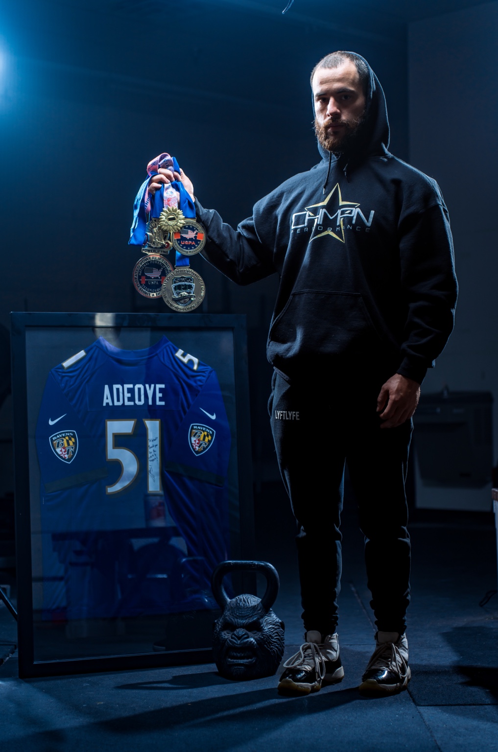 Matt holding medals alongside a football jersey